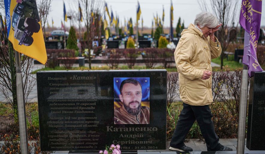 Vira Katanenko, 66, cries while visiting a grave of her son Andrii Katanenko, a Ukrainian serviceman of 59th brigade at the cemetery in Bucha, Ukraine, on Sunday, Nov. 23, 2025. (AP Photo/Evgeniy Maloletka)