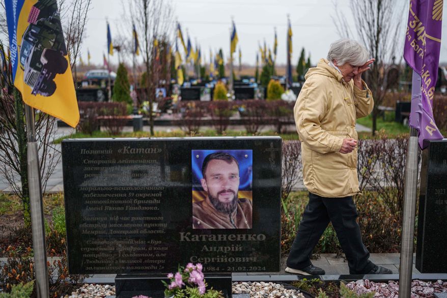 Vira Katanenko, 66, cries while visiting a grave of her son Andrii Katanenko, a Ukrainian serviceman of 59th brigade at the cemetery in Bucha, Ukraine, on Sunday, Nov. 23, 2025. (AP Photo/Evgeniy Maloletka)