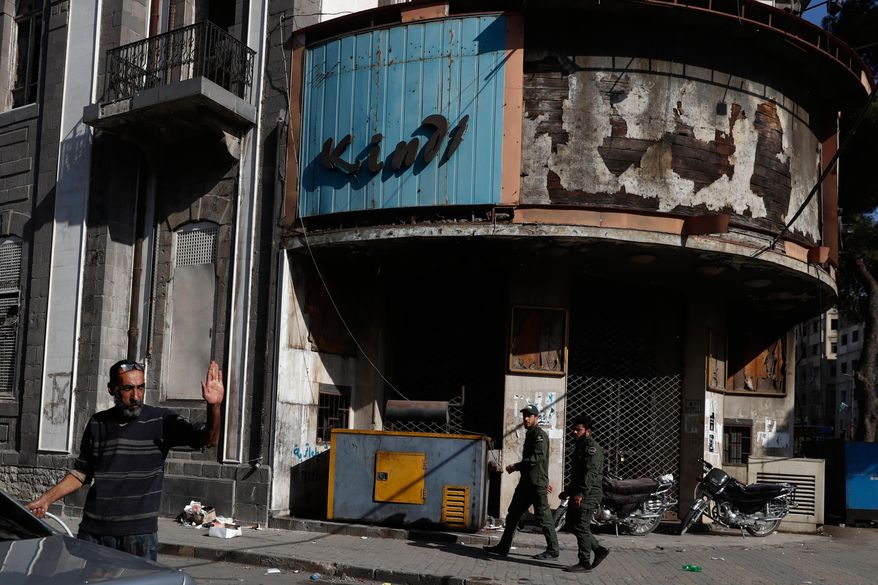 Syrian army fighters walk past an abandoned cinema in downtown Homs, Syria, Friday, Nov. 21, 2025. (AP Photo/Omar Sanadiki) ** FILE **