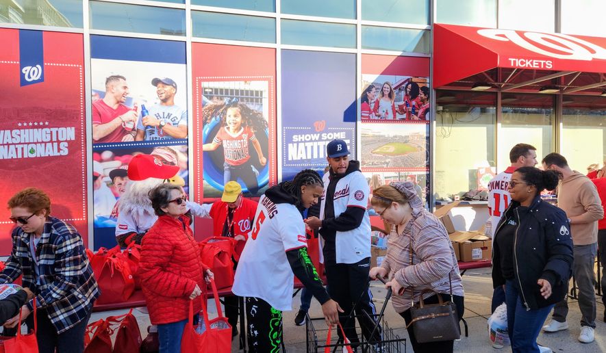 Washington Nationals shortstop C.J. Abrams (left) and outfielder James Wood distributed Thanksgiving meals to families in need outside of National Park in the District on Monday as part of the franchise's eighth annual "Turkeypalooza." (Liam Griffin/The Washington Times)