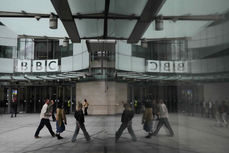 Pedestrians are reflected as they walk outside BBC Broadcasting House in London, Tuesday, Nov. 11, 2025. (AP Photo/Kirsty Wigglesworth, file)