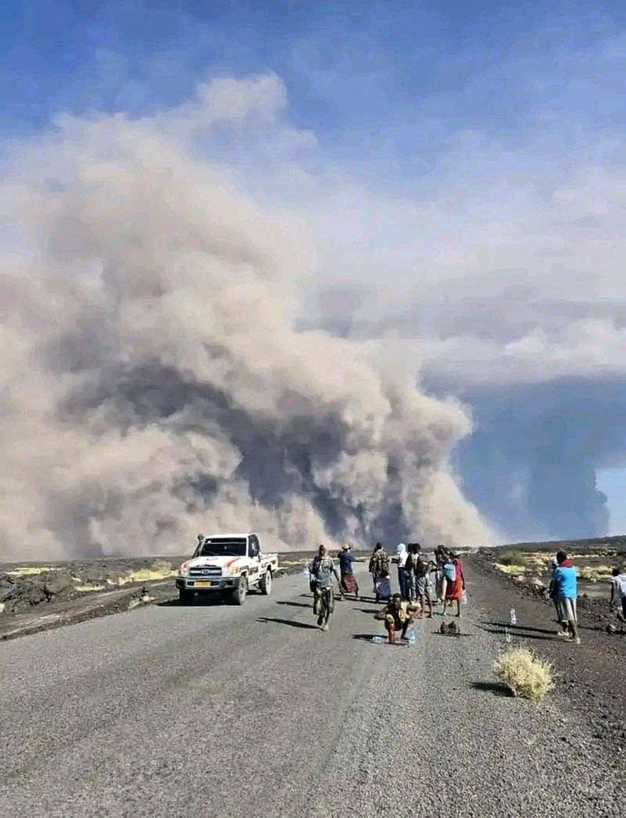 In this photo released by the Afar Government Communication Bureau, people watch ash billow from the first time eruption of the Hayli Gubbi Volcano in Ethiopia's Afar region Sunday, Nov. 23, 2025. (Afar Government Communication Bureau via AP)