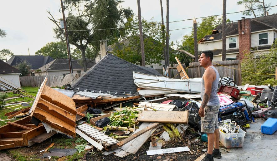 Jose Rosas surveys damage to Guillermo Vargas' home as while helping clean up storm damage in the Memorial Northwest subdivision, in Spring, Texas, Monday, Nov. 24, 2025. (Brett Coomer/Houston Chronicle via AP)