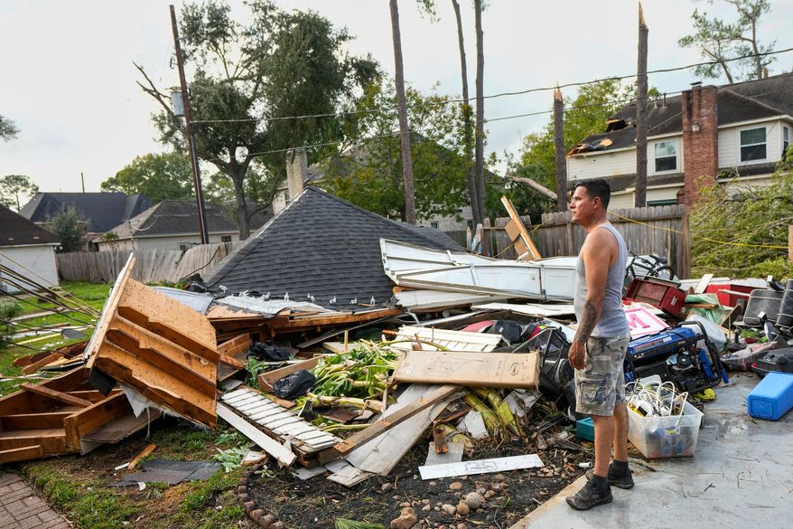 Jose Rosas surveys damage to Guillermo Vargas' home as while helping clean up storm damage in the Memorial Northwest subdivision, in Spring, Texas, Monday, Nov. 24, 2025. (Brett Coomer/Houston Chronicle via AP)