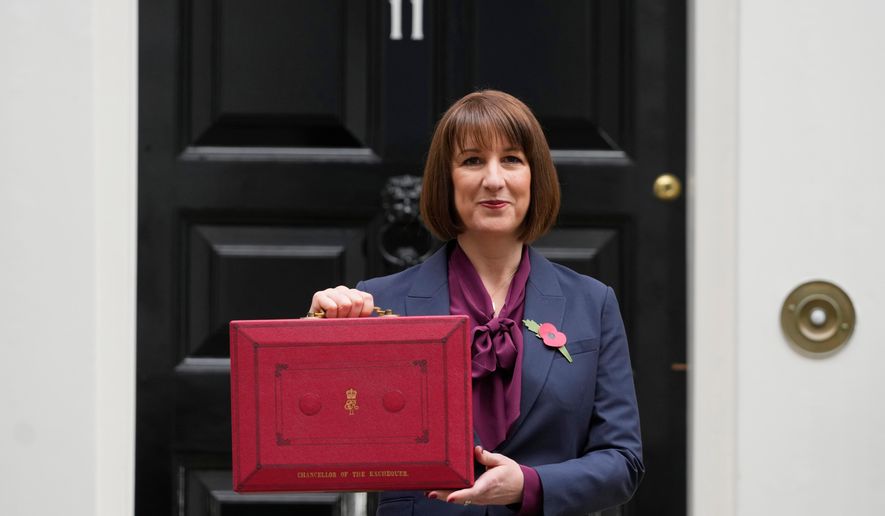 FILE - Britain's Chancellor of the Exchequer, Rachel Reeves, holds up the traditional red ministerial box containing her budget speech, as she poses for the media outside No 11 Downing Street, before departing to the House of Commons to deliver the budget in London, Wednesday, Oct. 30, 2024. (AP Photo/Kirsty Wigglesworth, File)