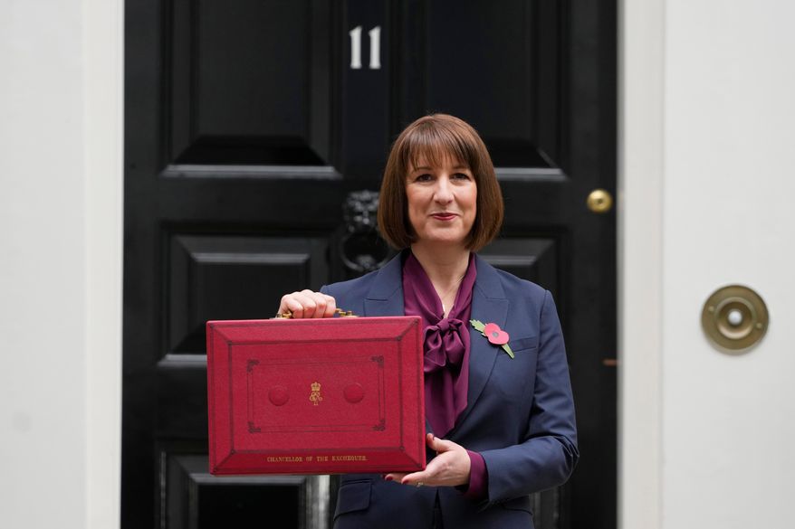 FILE - Britain's Chancellor of the Exchequer, Rachel Reeves, holds up the traditional red ministerial box containing her budget speech, as she poses for the media outside No 11 Downing Street, before departing to the House of Commons to deliver the budget in London, Wednesday, Oct. 30, 2024. (AP Photo/Kirsty Wigglesworth, File)