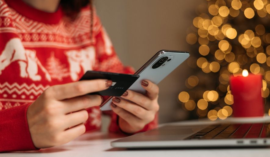 Female hands on the phone and laptop with credit card. File photo credit: Yarrrrrbright via Shutterstock.