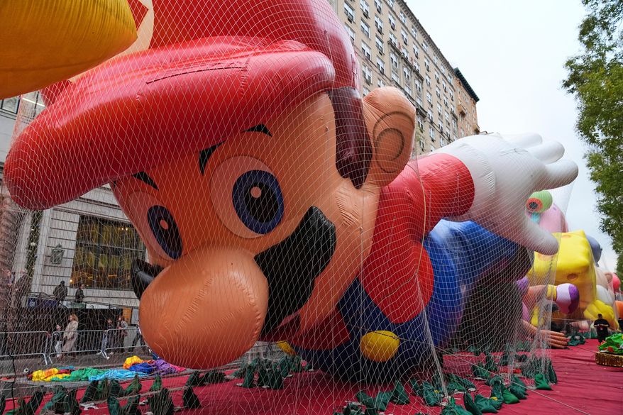 People pass Mario balloon during inflation for the 99th Macy's Thanksgiving Day Parade Wednesday, Nov. 26, 2025, in New York. (AP Photo/Frank Franklin II)