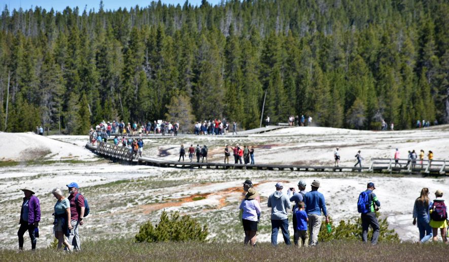 FILE - Tourists walk along a boardwalk in Upper Geyser Basin on June 22, 2022, in Yellowstone National Park, Wyo. (AP Photo/Matthew Brown, File)