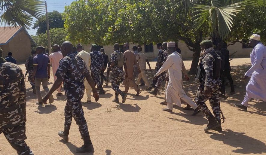 Police and government officials walk past St. Mary's Catholic Primary and Secondary School where gunmen on Friday abducted children and staff in Papiri community, Nigeria, Tuesday, Nov.25, 2025. (AP Photo/Yunusa Umar )