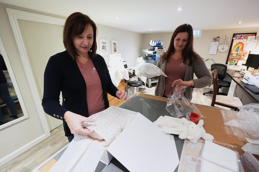 Fran Poirier, left, and her sister, Sue Bacarro, right, fill orders at their Etsy shop Digi Wildflowers, Thursday, Oct. 30, 2025, in Windsor, Ontario, Canada. (AP Photo/Paul Sancya)
