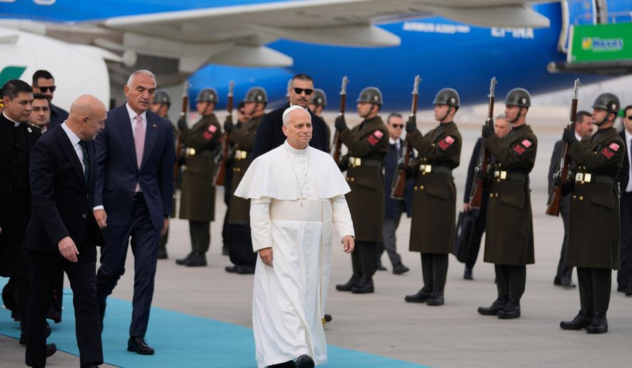 Pope Leo XIV walks as he is welcomed upon his arrival at Esenboga International Airport in Ankara, Turkey, Thursday, Nov. 27, 2025, marking the beginning of his first foreign trip. (AP Photo/Khalil Hamra)