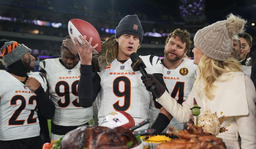 Cincinnati Bengals quarterback Joe Burrow (9) joined by safety Geno Stone (22), defensive end Myles Murphy (99) and center Ted Karras (64) talks with NBC Sports sideline reporter Melissa Stark, right, after NFL football game against the Baltimore Ravens, Thursday, Nov. 27, 2025, in Baltimore. (AP Photo/Stephanie Scarbrough)