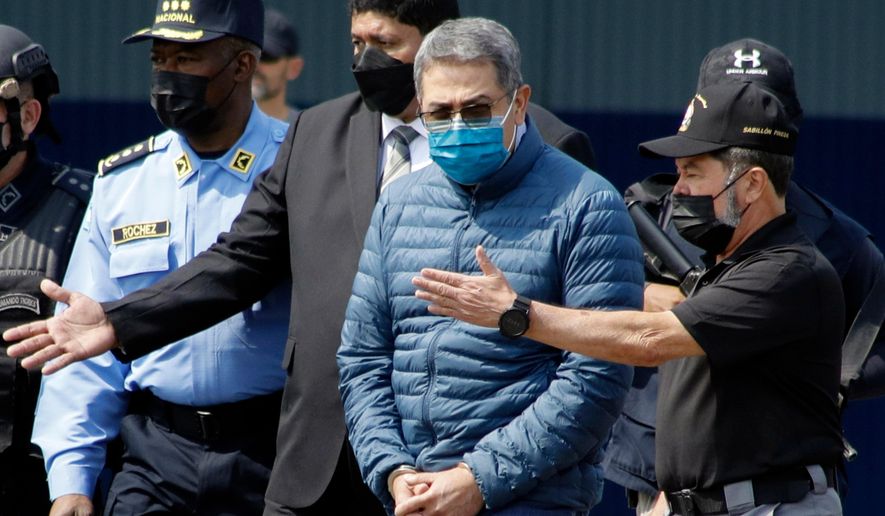 Former Honduran President Juan Orlando Hernandez, second from right, is taken in handcuffs to a waiting aircraft as he is extradited to the United States, at an Air Force base in Tegucigalpa, Honduras, April 21, 2022. (AP Photo/Elmer Martinez, File)