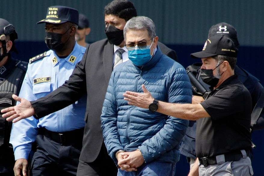 Former Honduran President Juan Orlando Hernandez, second from right, is taken in handcuffs to a waiting aircraft as he is extradited to the United States, at an Air Force base in Tegucigalpa, Honduras, April 21, 2022. (AP Photo/Elmer Martinez, File)