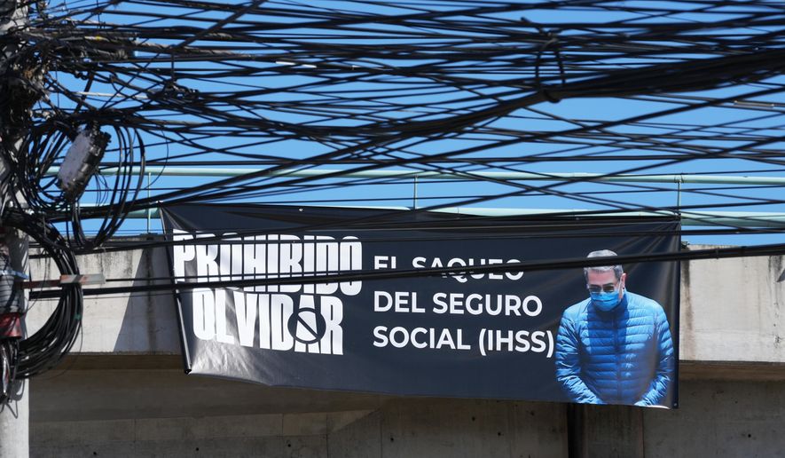 A banner with an image of former Honduran President Juan Orlando Hernandez with a message that reads in Spanish: "It is forbidden to forget the looting of social security" hangs on a bridge in Tegucigalpa, Honduras, Saturday, Nov. 29, 2025, a day after President Donald Trump said he plans to pardon Hernandez for a 2024 drug trafficking sentence. (AP Photo/Moises Castillo)