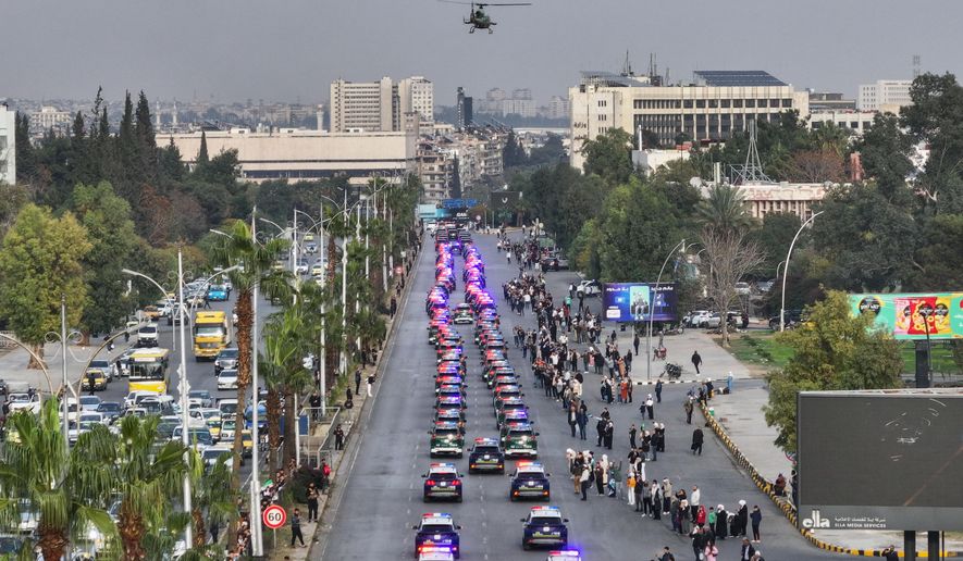 A Syrian army helicopter flies overhead as Ministry of Interior vehicles drive in formation through central Damascus during an official rollout of their new visual identity, as crowds watch from the roadside, in Damascus, Syria, Saturday, Nov. 29, 2025. (AP Photo/Ghaith Alsayed)