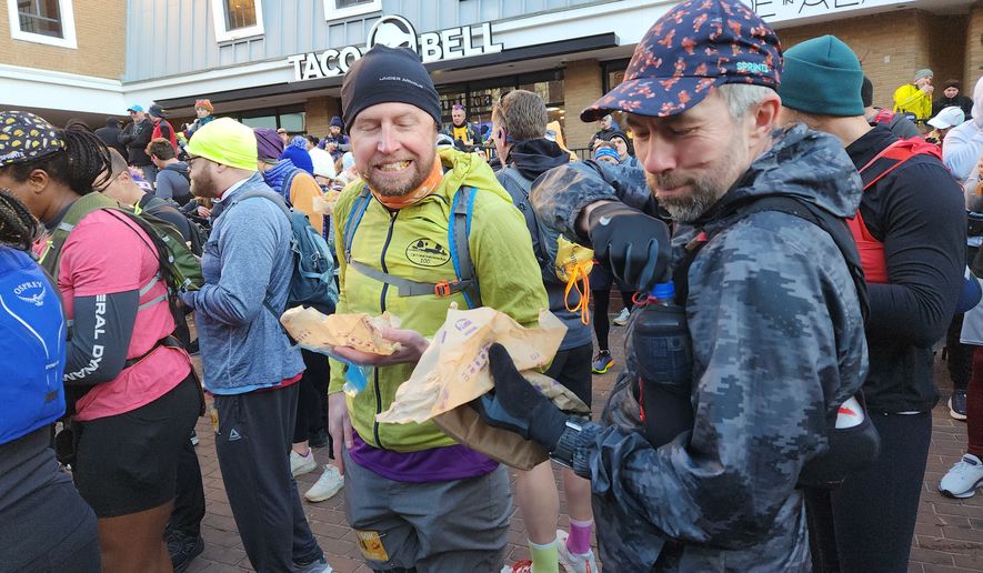 Runners eat their first burrito at a Taco Bell 50K in Alexandria, Virginia on Nov. 29, 2025. Hundreds of racers turned out for the ultramarathon, which combined a traditional race with the challenge of eating several Taco Bell menu items. (Liam Griffin/The Washington Times)