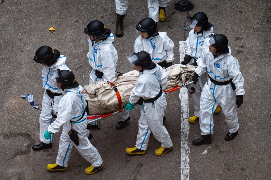Police remove what appears to be a body bag from the site of a deadly Wednesday fire at Wang Fuk Court, a residential estate in the Tai Po district of Hong Kong's New Territories on Sunday, Nov. 30, 2025. (AP Photo/Chan Long Hei)