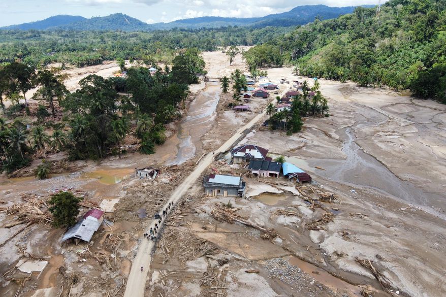 People walk along a road in a village affected by a flash flood in Batang Toru, North Sumatra, Indonesia, Monday, Dec. 1, 2025. (AP Photo/Binsar Bakkara)