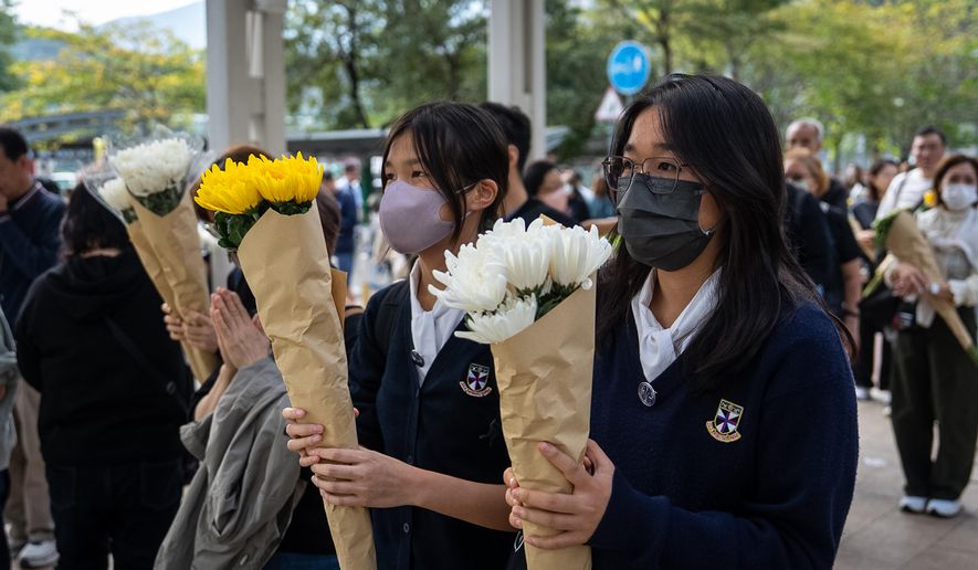 People offer flowers for the victims near the site of a deadly Wednesday fire at Wang Fuk Court, a residential estate in the Tai Po district of Hong Kong's New Territories on Monday, Dec. 1, 2025. (AP Photo/Chan Long Hei)