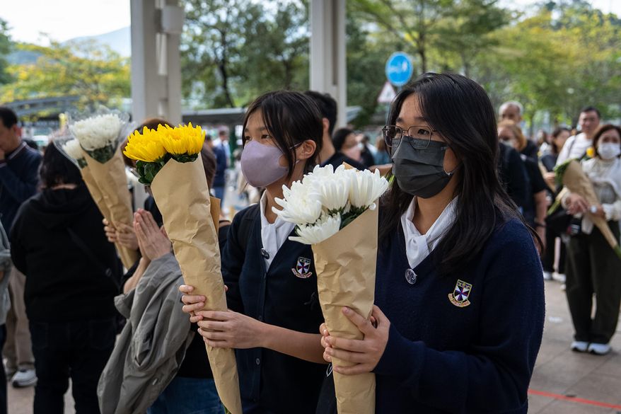 People offer flowers for the victims near the site of a deadly Wednesday fire at Wang Fuk Court, a residential estate in the Tai Po district of Hong Kong's New Territories on Monday, Dec. 1, 2025. (AP Photo/Chan Long Hei)