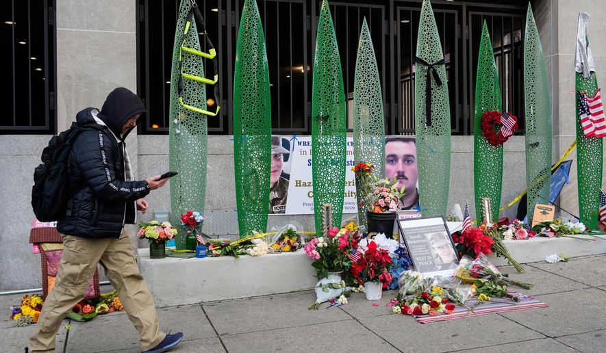 A person walks past a makeshift memorial for U.S. Army Spc. Sarah Beckstrom and U.S. Air Force Staff Sgt. Andrew Wolfe outside of Farragut West Station, near the site where the two National Guard members were shot, Monday, Dec. 1, 2025, in Washington. (AP Photo/Julia Demaree Nikhinson)