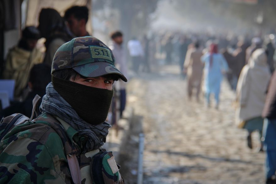 A Taliban policeman looks on as a crowd heads toward a stadium to attend the public execution carried out by Taliban authorities of a man sentenced by the Supreme Court for killing 13 members of a family, including children, earlier this year, in the eastern city of Khost, Afghanistan, Tuesday, Dec. 2, 2025. (AP Photo/Saifullah Zahir)