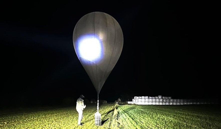 In this undated photo released by the State Border Guard Service, an officer inspects a balloon used to carry cigarettes into Lithuania, because Belarussian smugglers often use them to ferry the contraband into the European Union (State Border Guard Service via AP, File)