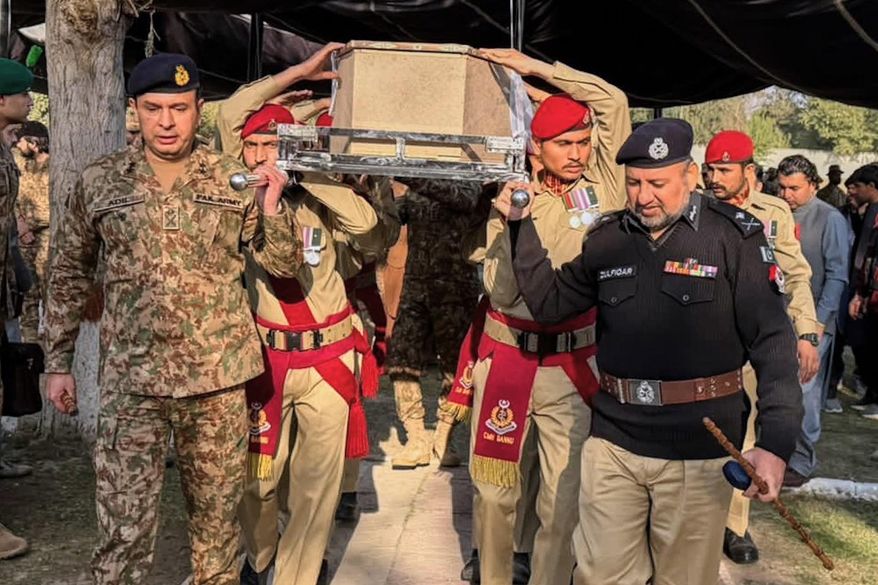 Army troops and a police officer carry the casket of a government administrator, who was killed by suspected militants, during his funeral prayer, in Bannu, Pakistan, Tuesday, Dec. 2, 2025. (AP Photo/Ammad Ehsan)