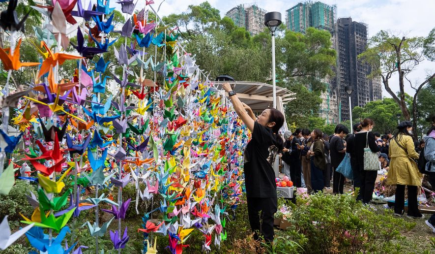 People hang paper cranes near the site of the fire at Wang Fuk Court, a residential estate in the Tai Po district of Hong Kong's New Territories on Wednesday, Dec 3, 2025. (AP Photo/Chan Long Hei)