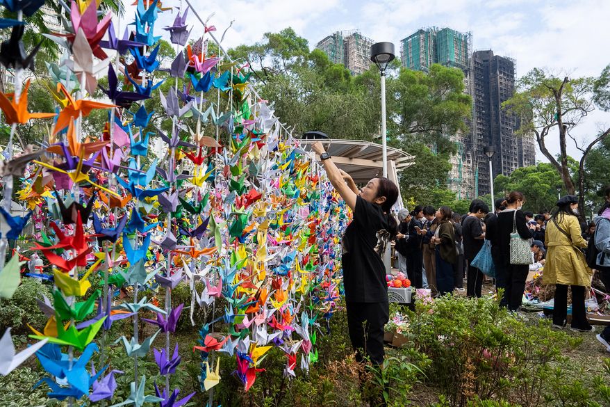People hang paper cranes near the site of the fire at Wang Fuk Court, a residential estate in the Tai Po district of Hong Kong's New Territories on Wednesday, Dec 3, 2025. (AP Photo/Chan Long Hei)