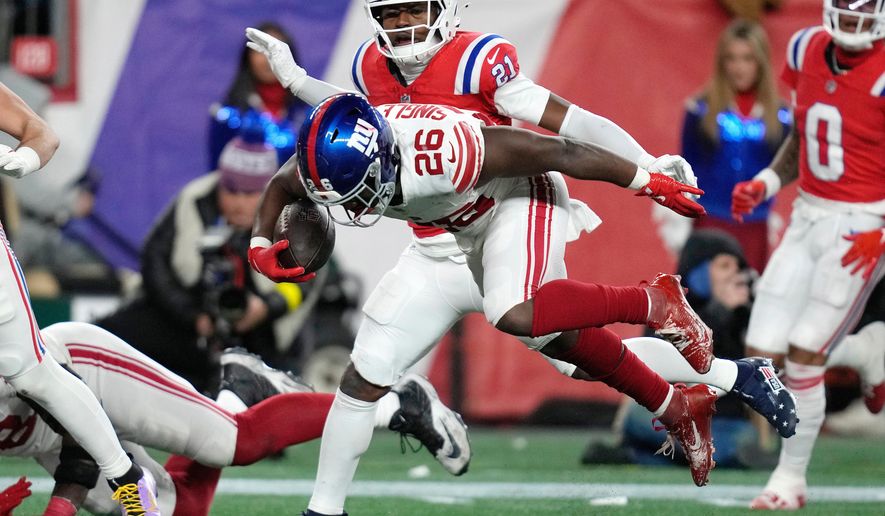 New York Giants running back Devin Singletary (26) scores a touchdown against New England Patriots safety Jaylinn Hawkins (21) during the second half of an NFL football game Monday, Dec. 1, 2025, in Foxborough, Mass. (AP Photo/Charles Krupa)
