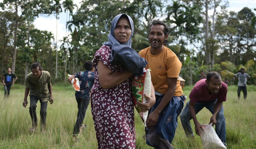 Flood survivors react as they receive relief goods during an aerial aid distribution using national disaster mitigation agency's helicopter in North Aceh, Indonesia, Thursday, Dec. 4, 2025. (AP Photo/Reza Saifullah)