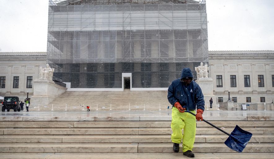 A worker shovels snow and ice in front of the Supreme Court building during the first snowfall of the winter season on Friday, Dec. 5, 2025, in Washington. (AP Photo/Mark Schiefelbein)