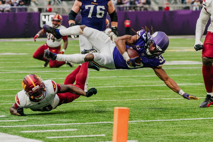 Minnesota Vikings Running Back Aaron Jones Sr. (33) dives over defender for some extra yards at U.S. Bank Stadium in Minneapolis, Minnesota. The Minnesota Vikings defeated the Washington Commanders 31-0 during NFL Week 14 on December 7th, 2025. (Photo by Jordan Sabillo for Washington Times)