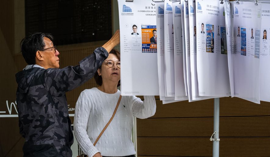 People read the candidates information at a polling station near the site of the fire at Wang Fuk Court in the Tai Po district during the Legislative Council General Election in Hong Kong on Sunday, Dec. 7, 2025. (AP Photo/Chan Long Hei)
