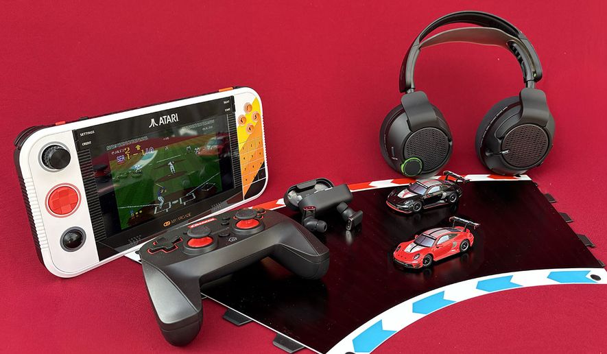 Atari's Gamestation Go, Carrera's Hybrid Highway Challenge with rechargeable gamepad, Status Audio's Pro X earbuds and Skullcandy's Crusher PLYR 720. (Photograph by Joseph Szadkowski / The Washington Times)