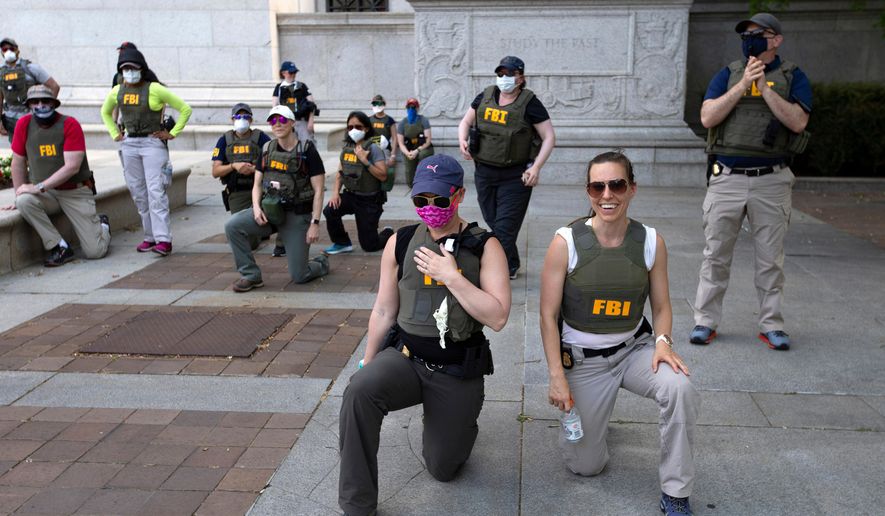 Federal Bureau of Investigation officers take a knee with demonstrators as they march on Pennsylvania Ave during a protest over the death of George Floyd on June 4, 2020, in Washington. (AP Photo/Jose Luis Magana, File)