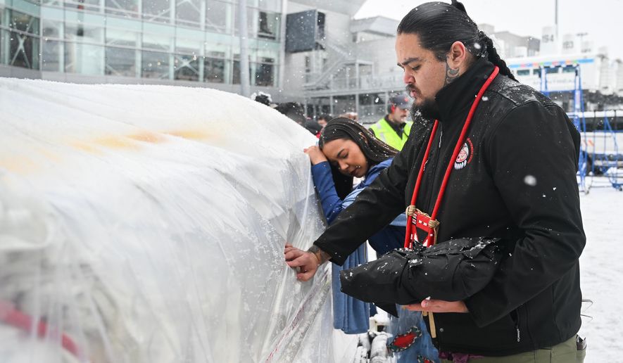 Katisha Paul of the Lil'wat and Tsartlip Nations, left, and Peyal Laceese of the Tsilhqot'in nation touch a crate containing indigenous artifacts and cultural items at Trudeau Airport in Montreal, Saturday, Dec. 6, 2025, after they were returned by the Vatican. (Graham Hughes /The Canadian Press via AP)