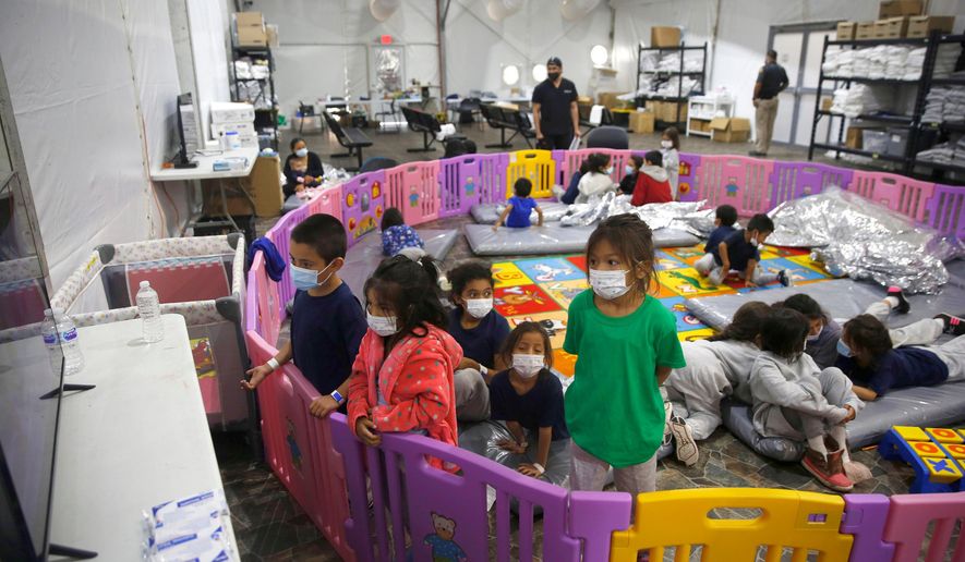 Unaccompanied migrant children watch television from inside a playpen at the U.S. Customs and Border Protection facility, the main detention center for unaccompanied children, March 30, 2021, in Donna, Texas. (AP Photo/Dario Lopez-Mills, Pool, File)
