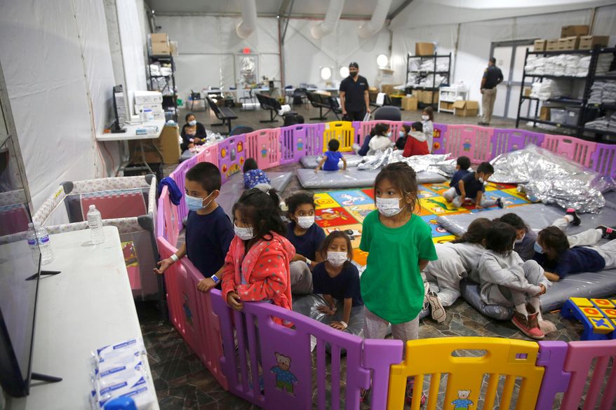 Unaccompanied migrant children watch television from inside a playpen at the U.S. Customs and Border Protection facility, the main detention center for unaccompanied children, March 30, 2021, in Donna, Texas. (AP Photo/Dario Lopez-Mills, Pool, File)
