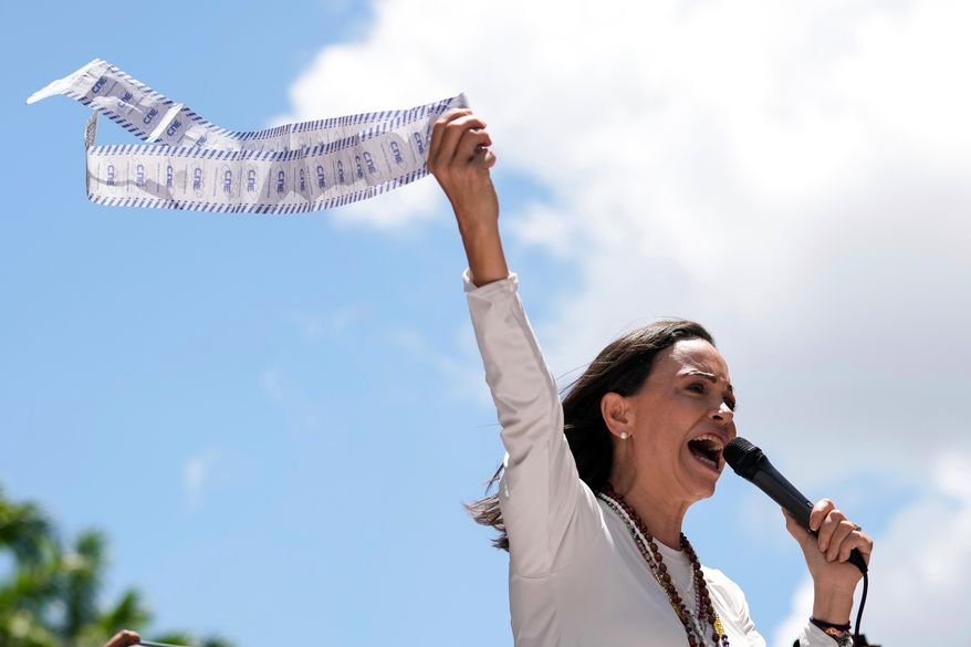 Opposition leader Maria Corina Machado displays vote tally sheets during a protest against the reelection of President Nicolas Maduro one month after the disputed presidential vote which she says the opposition won by a landslide, in Caracas, Venezuela, Wednesday, Aug. 28, 2024. (AP Photo/Ariana Cubillos, file)