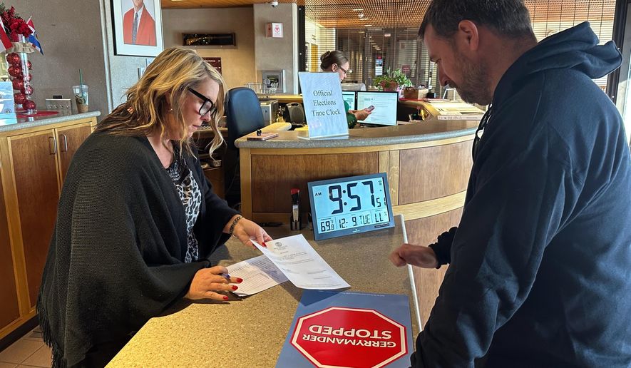 Chrissy Peters, director of elections for the Missouri secretary of state, approves the paperwork showing that petition signatures were submitted Tuesday, Dec. 9, 2025, in Jefferson City by People Not Politicians Executive Director Richard von Glahn calling for a referendum election on new U.S. House districts passed by the Missouri legislature. (AP Photo/David A. Lieb)
