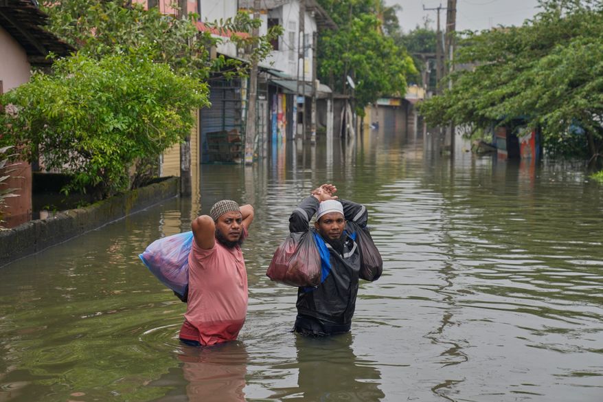 FILE - People wade through floodwaters in the aftermath of Cyclone Ditwah in Colombo, Sri Lanka, Nov. 29, 2025. (AP Photo/Eranga Jayawardena, File)