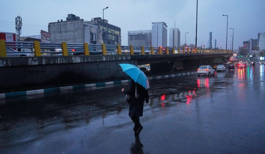 A woman holds an umbrella while crossing a street as rain falls in Tehran, Iran, Wednesday, Dec. 10, 2025. (AP Photo/Vahid Salemi)