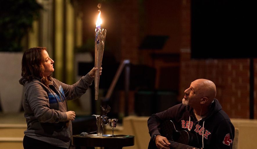 Rabbi Jonathan Aaron plays guitar while Cantor Lizzie Weiss helps during the Havdalah candle ceremony at the conclusion of a sound bath at Temple Emanuel, Saturday, Dec. 6, 2025, in Beverly Hills, Calif. (AP Photo/Allison Dinner)