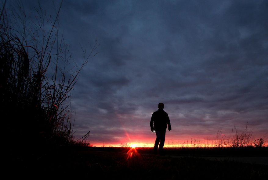 A man walks along a trail during sunset near Manhattan, Kan., on Nov. 20, 2015. (AP Photo/Charlie Riedel, File)