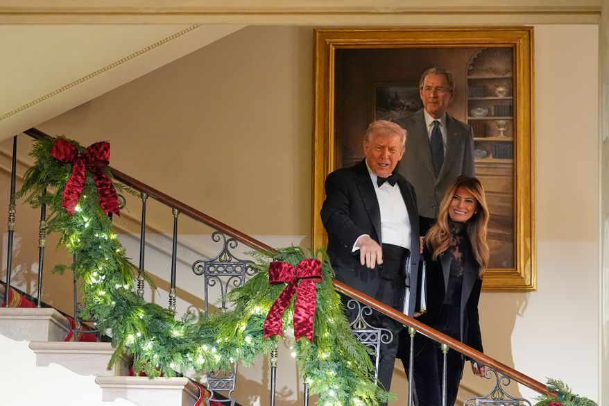 President Donald Trump and first lady Melania Trump pass a portrait of former President George W. Bush as they walk down into the Grand Foyer of the White House during the Congressional Ball, Thursday, Dec. 11, 2025, in Washington. (AP Photo/Alex Brandon)