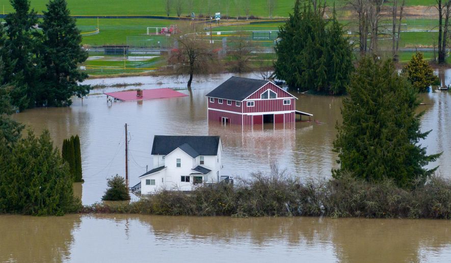 A n aerial view of a home and a barn surrounded by floodwaters in Snohomish, Wash., Thursday, Dec. 11, 2025. (AP Photo/Stephen Brashear)